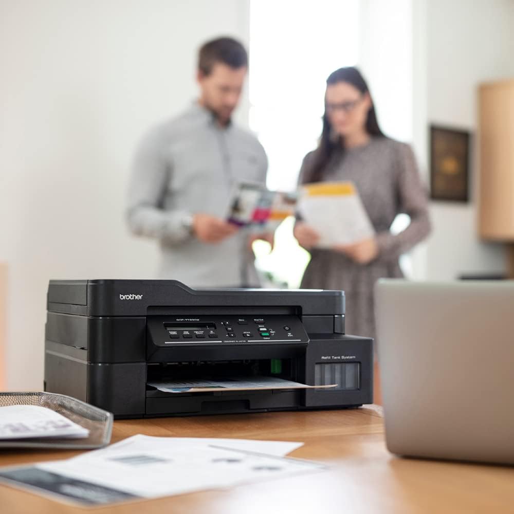 Brother all-in-one ink tank printer on desk with paper feeding from the output tray