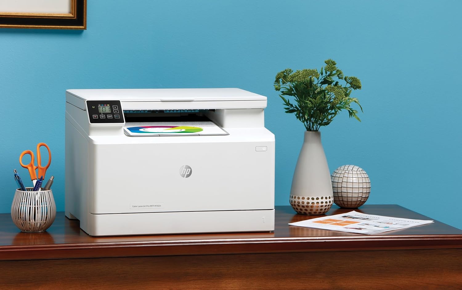 HP Color LaserJet Pro MFP M182n color laser printer on desk showing control panel and output