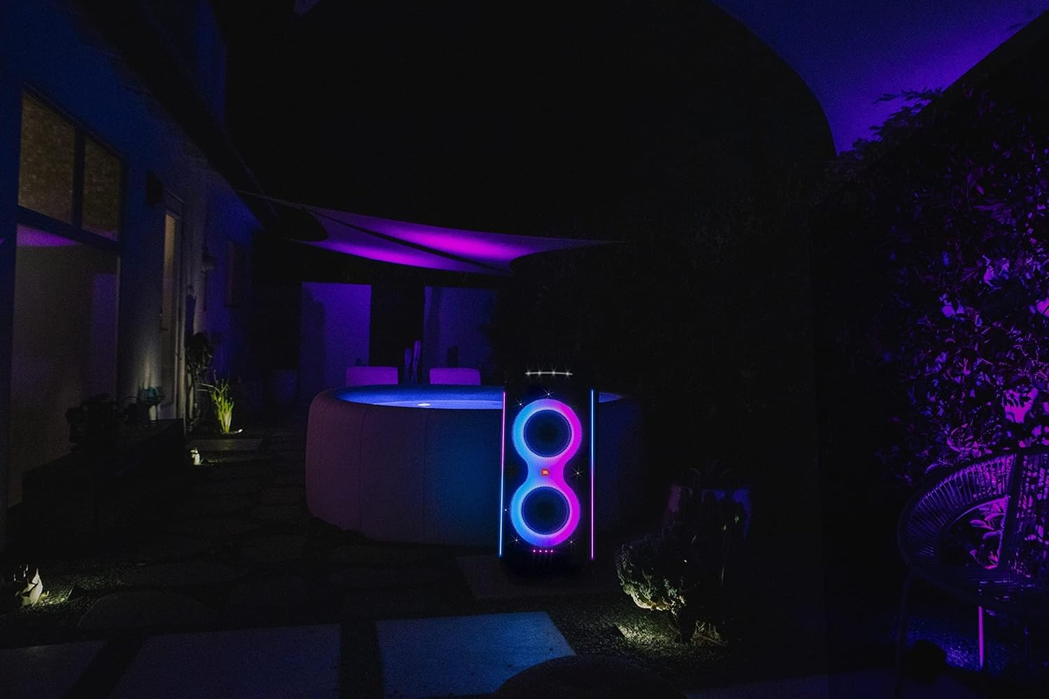 JBL PartyBox speaker in a dark outdoor setting with bright purple glowing LED rings