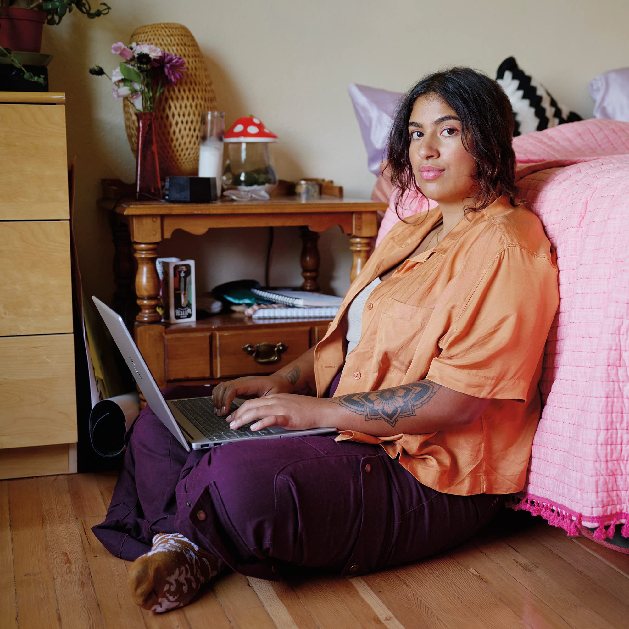 Person using silver HP laptop on bed, screen facing forward and keyboard visible