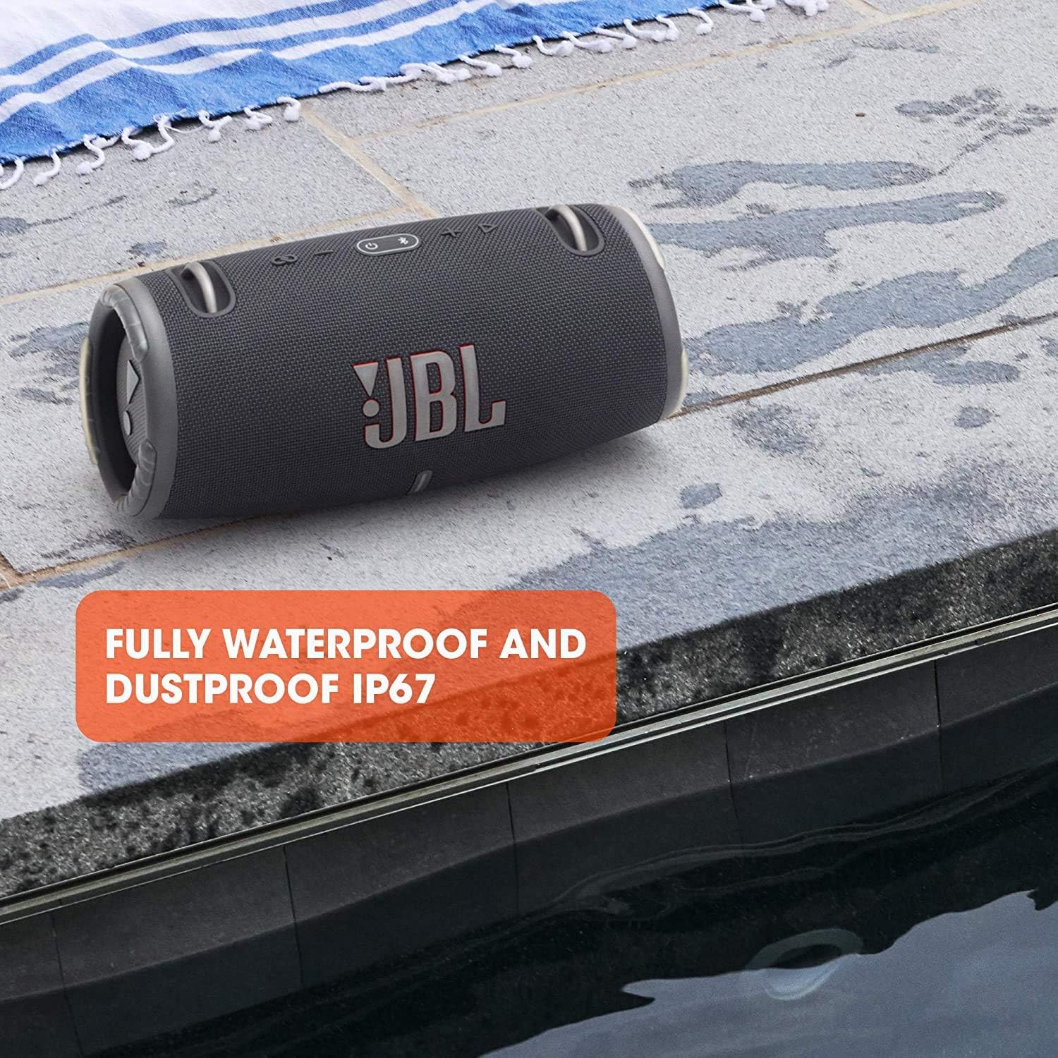 Portable waterproof speaker with JBL logo on dark fabric grille outdoors on walkway