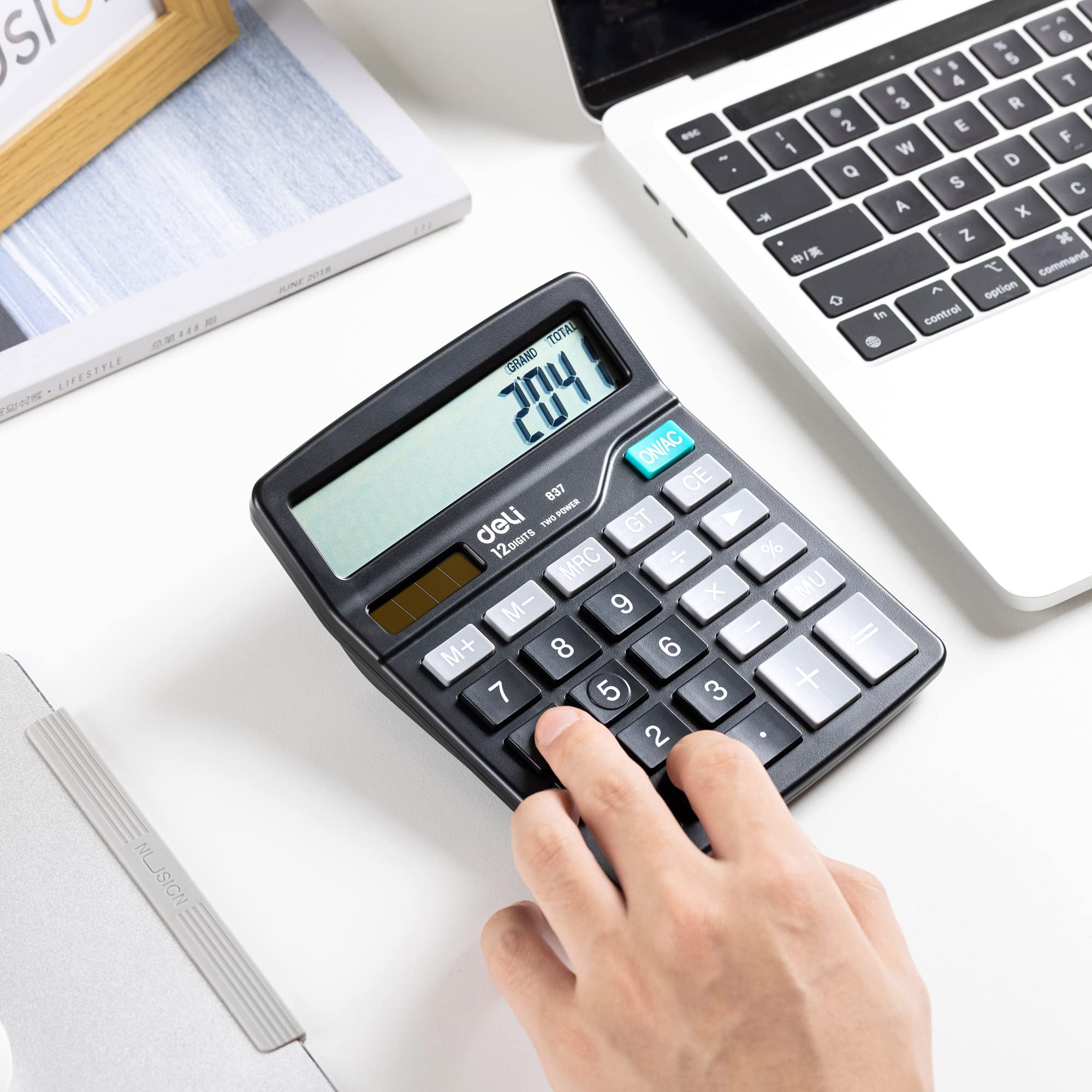 Hand using desktop calculator with LCD display and numeric keypad