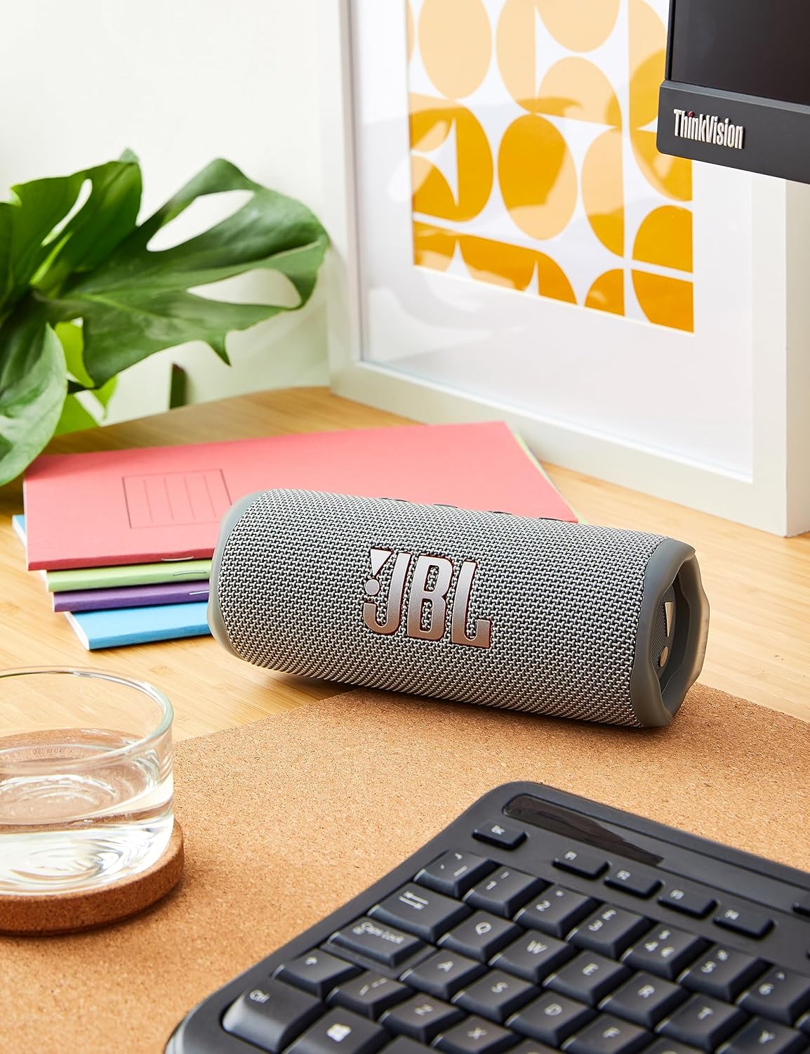 Blue portable Bluetooth speaker on desk near keyboard and books