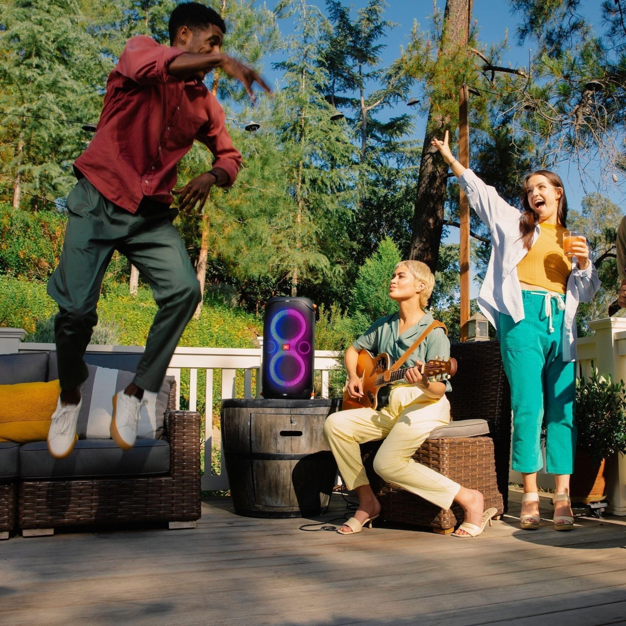 Portable party speaker with glowing LED rings as people sing with wireless handheld microphones.