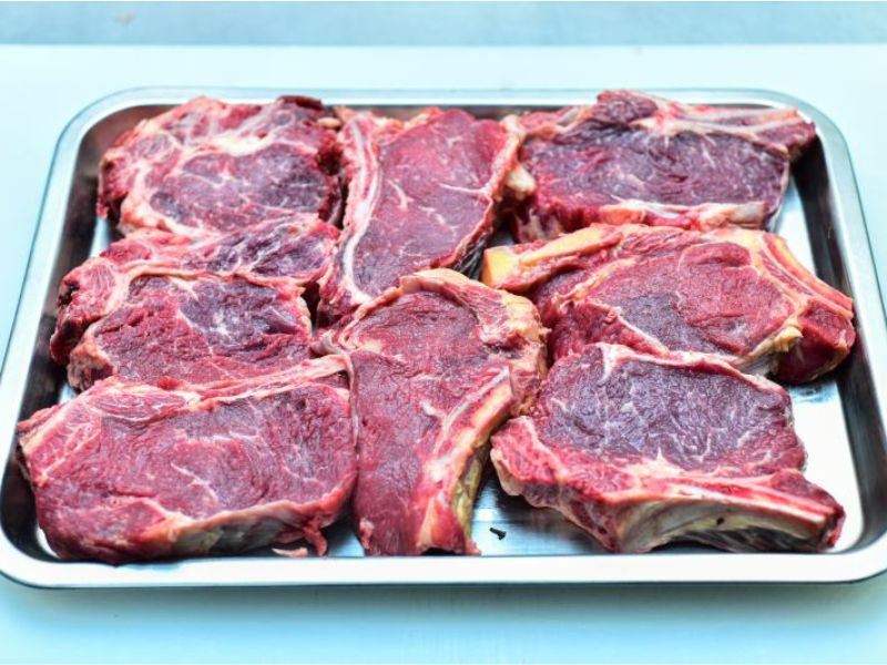 Raw beef chops with visible marbling in metal tray