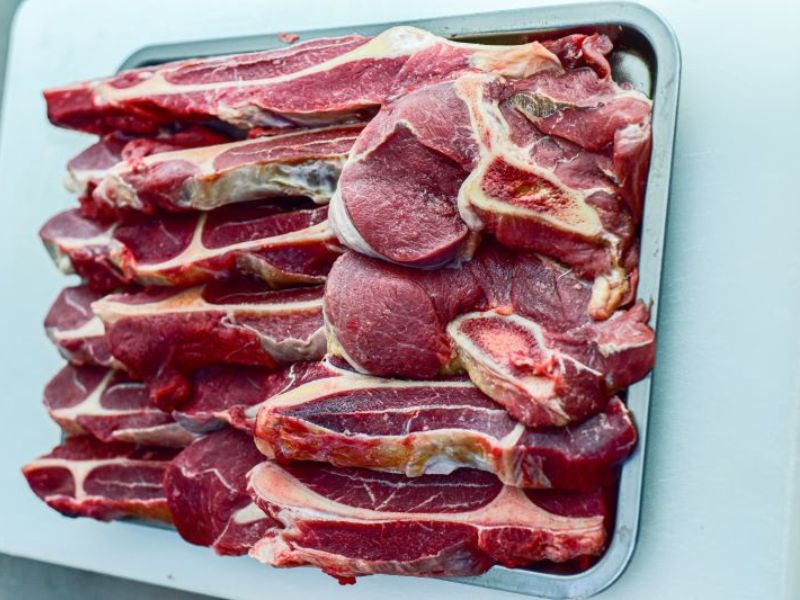 Raw beef shoulder cuts with visible fat marbling, tray of assorted pieces