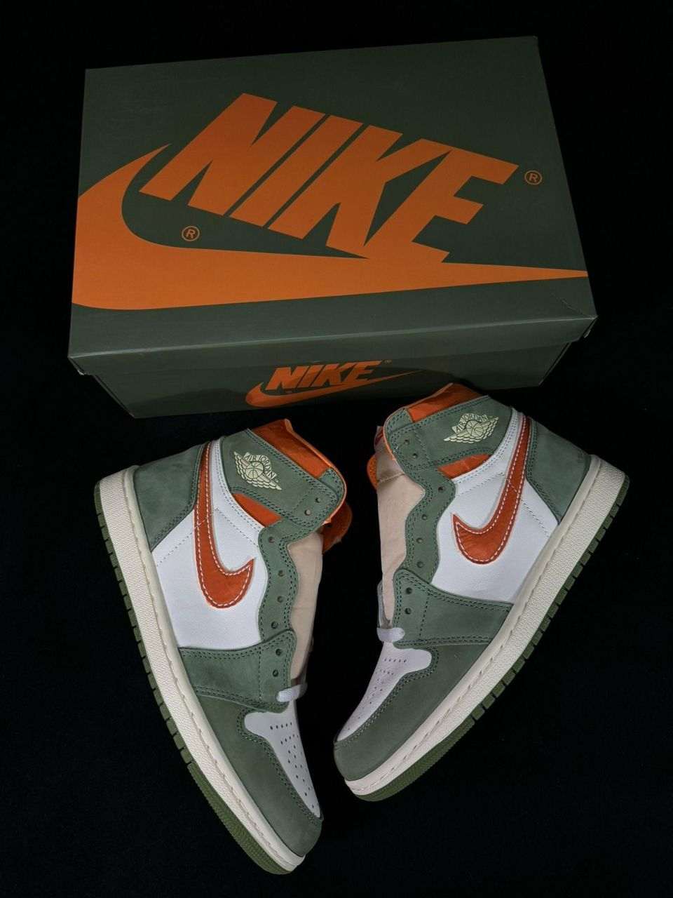 Air Jordan 1 sneakers with green suede, white uppers, orange Swoosh, shown with box