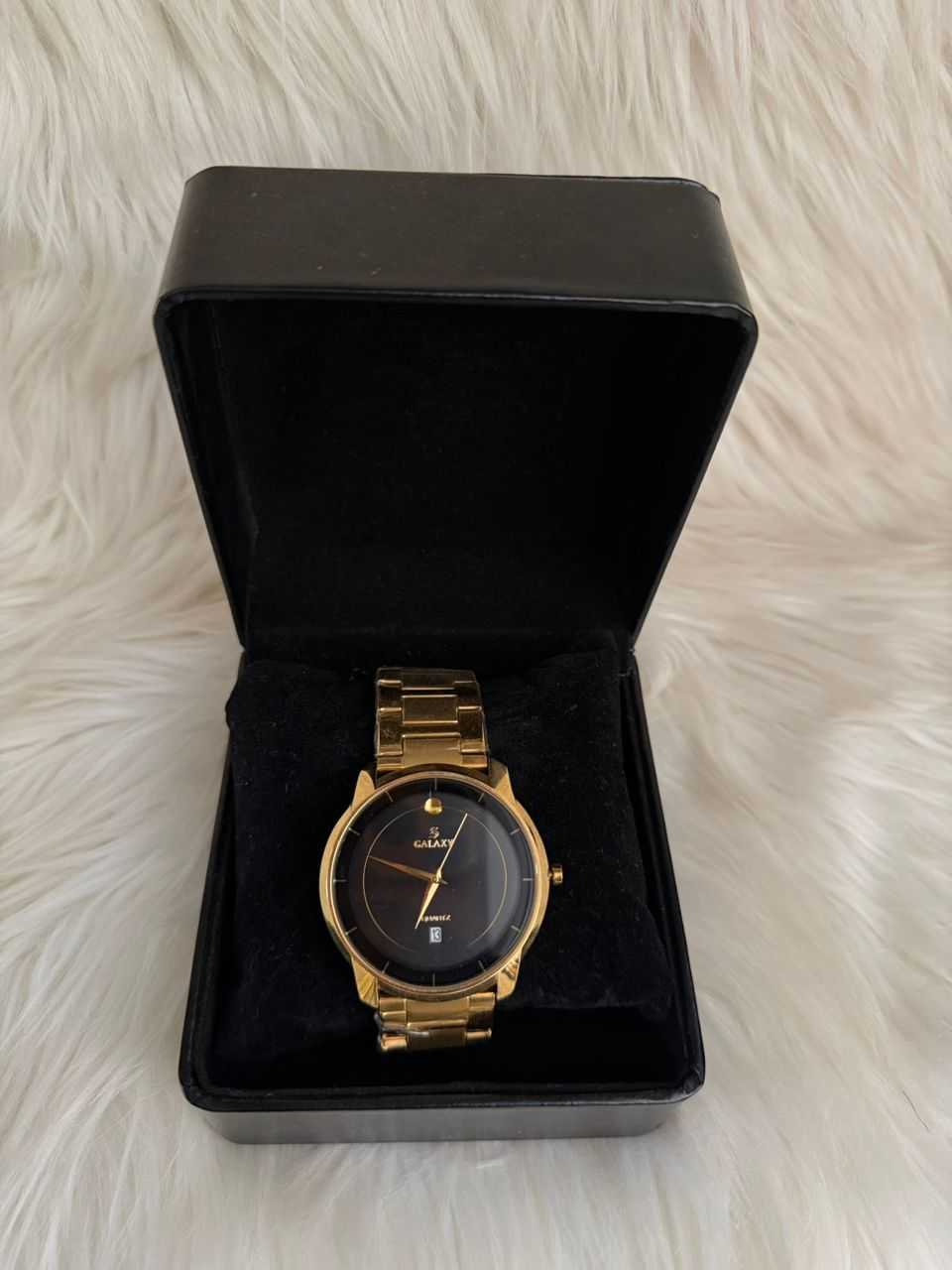 Gold minimalist analog watch with dark dial, displayed in black gift box