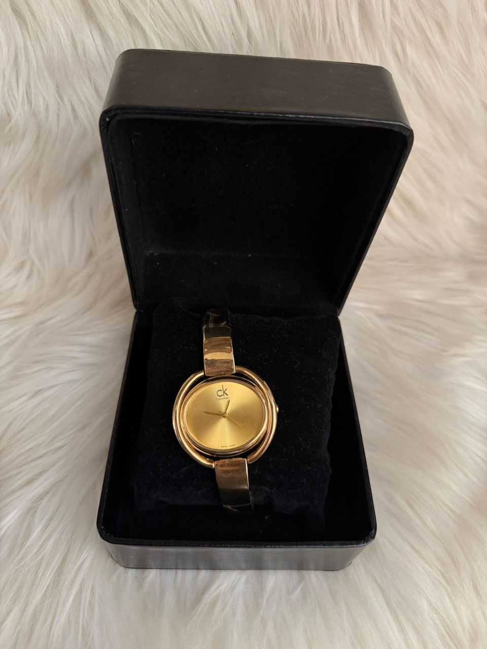 Gold CK bracelet watch with round dial and black leather strap in display box