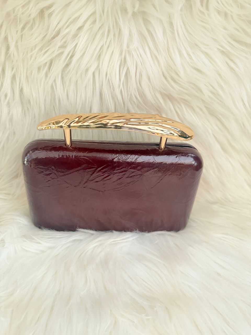 Dark burgundy patent clutch handbag with gold-tone frame handle