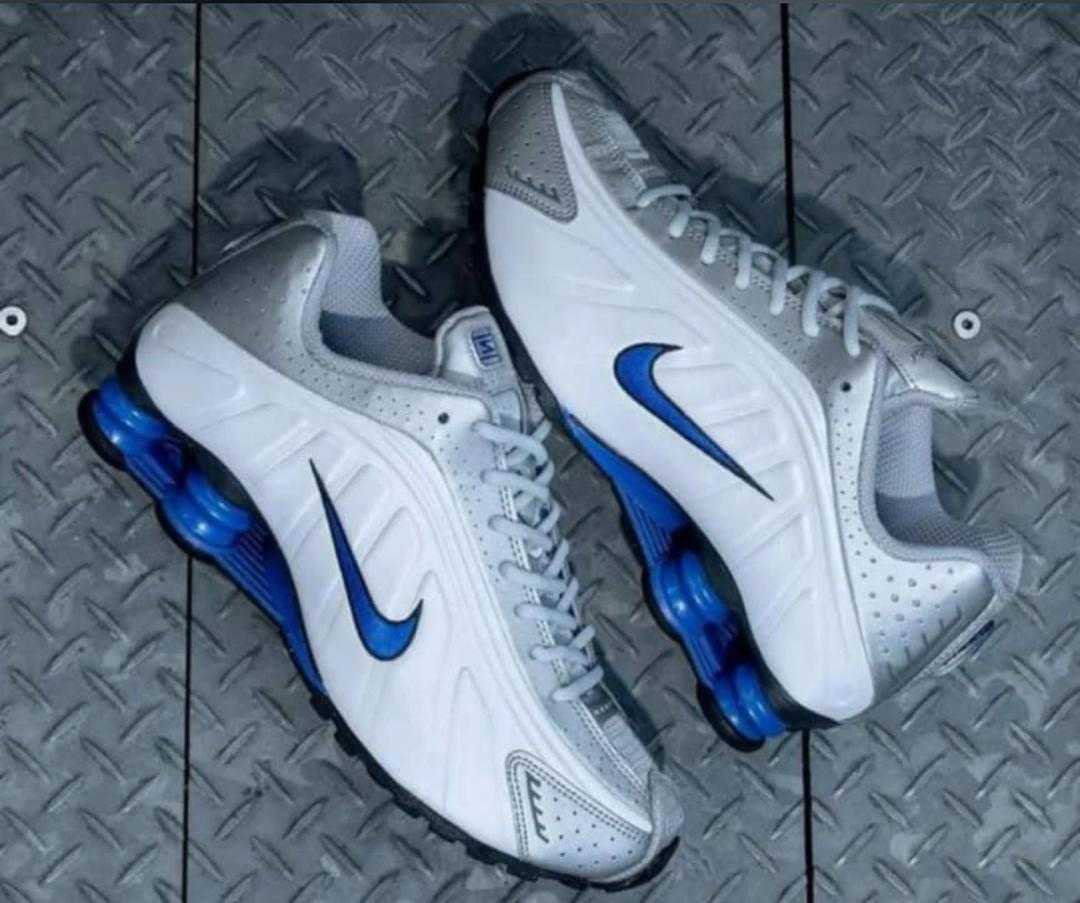 White Nike Shox R4 lace-up sneakers with blue Swoosh and blue cushioning pods