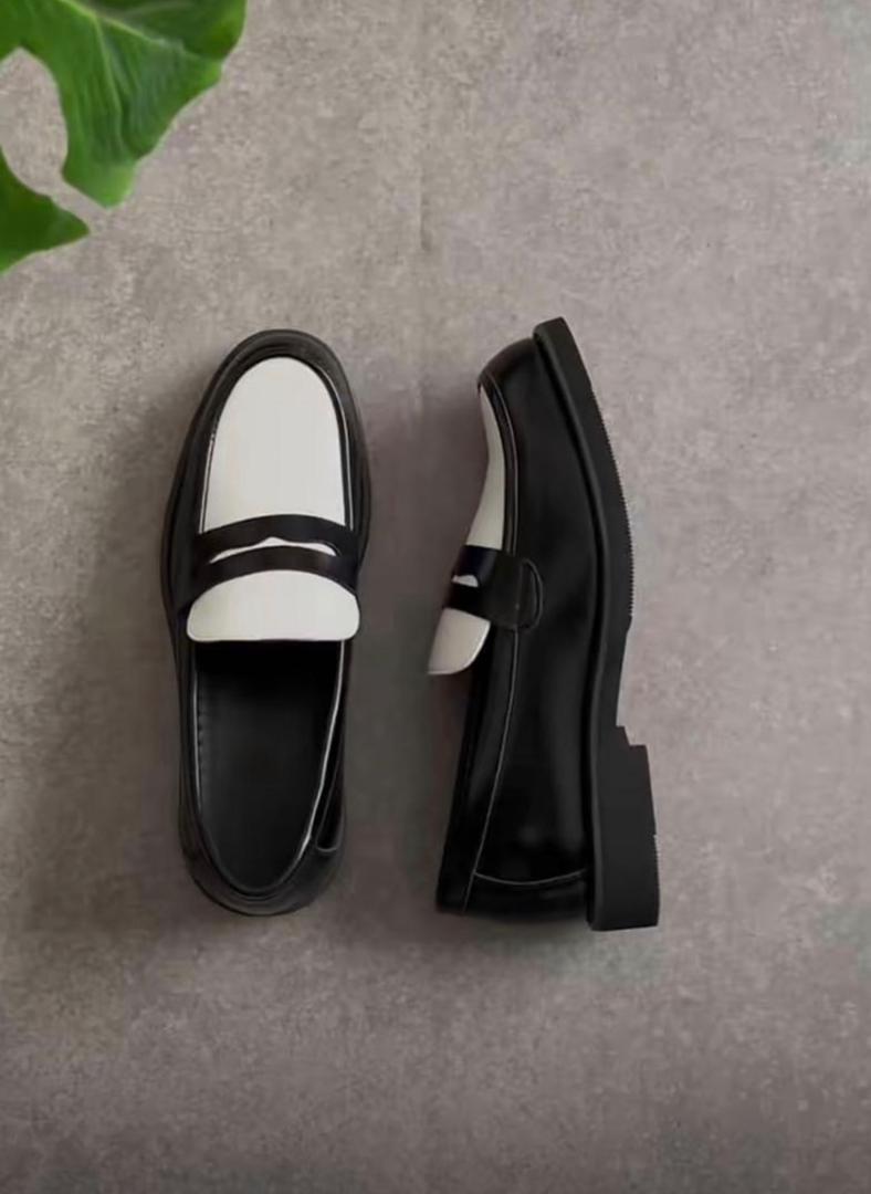 Black and white leather loafers with white trim, slip-on style, shown from top and side