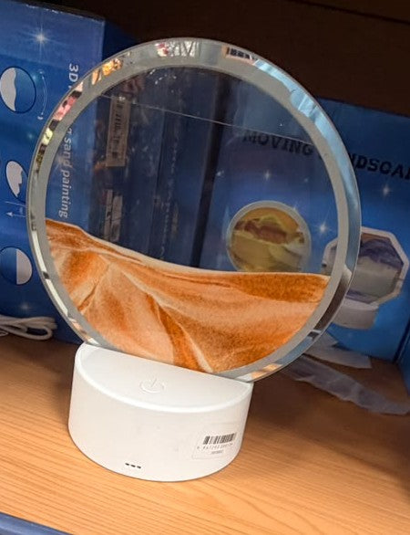 Circular moving sand display with orange sand layers in a clear dome